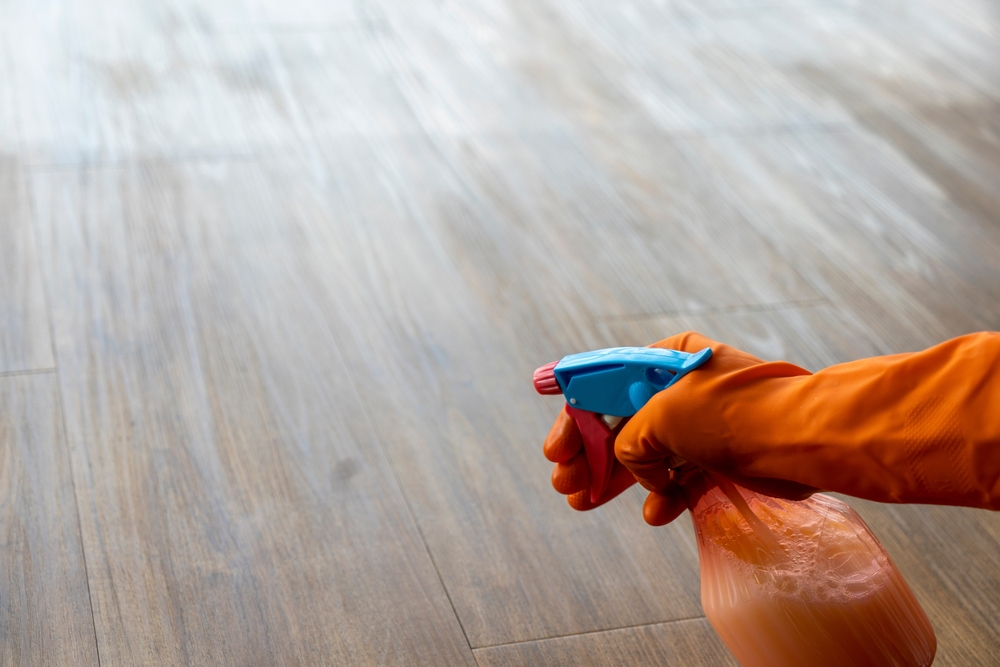 person cleaning vinyl flooring with spray bottle