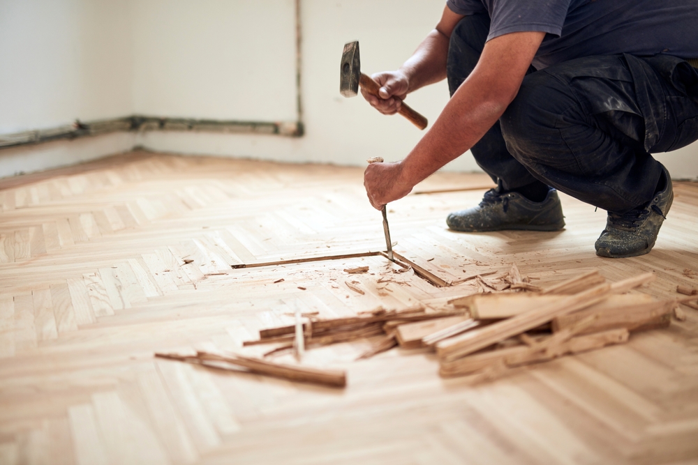 man tearing up hardwood flooring for repair