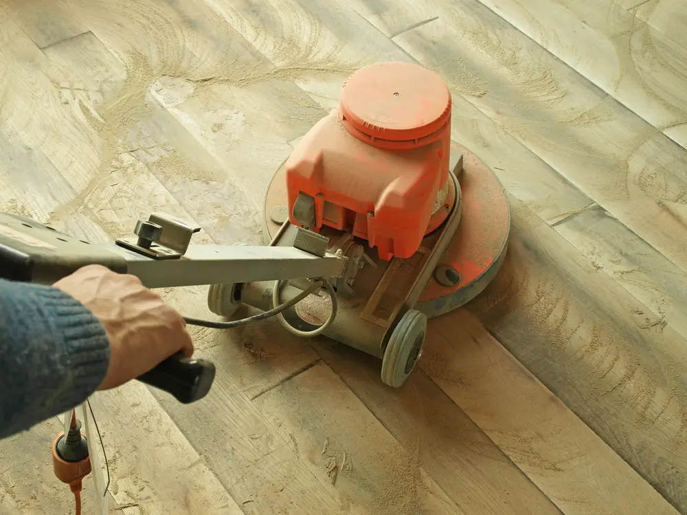 Man preparing flooring for hardwood refinish vs replacement