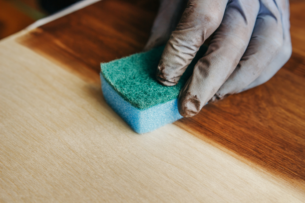 person refinishing hardwood with stain